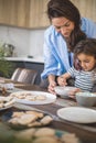 Mom and daughter prepare icing for gingerbread in their home kitchen. Beat with a blender. The girl helps the woman. Royalty Free Stock Photo