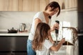 Mom and daughter prepare icing for gingerbread in their home kitchen. Beat with a blender. The girl helps the woman. Royalty Free Stock Photo