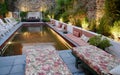 Stylish illuminated backyard pool in lush green tropical garden.