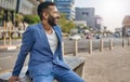 Stylish Indian businessman sitting on bench in busy city