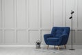 Stylish interior with armchair and floor lamp near white wall in room, space for text Royalty Free Stock Photo