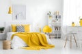 Stylish interior of bright modern bedroom with a big comfortable bed and yellow details. Cozy functional berdoom interior design Royalty Free Stock Photo