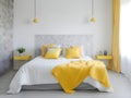 Stylish interior of bright modern bedroom with a big comfortable bed and yellow details. Cozy functional berdoom interior design Royalty Free Stock Photo