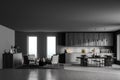 Stylish interior of dark grey modern kitchen room with dining table and chairs. Armchairs livingroom zone open space Royalty Free Stock Photo