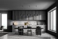 Stylish interior of dark grey modern kitchen room with dining table and chairs. Open space zone. Big window Royalty Free Stock Photo