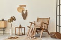 Stylish interior design of living room with wooden armchair, coffee table, furniture, rattan decoration, dried flowers.