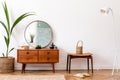 Round mirror on the wooden commode in stylish, vintage interior.