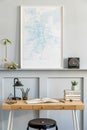 Stylish interior of home office room with black mock up poster map, wooden desk, black stool, clock, books, plants, office supplie Royalty Free Stock Photo