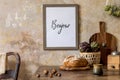 Stylish interior of kitchen space with wooden table, brown mock up photo frame, herbs, vegetables, tea pot, cups . Royalty Free Stock Photo