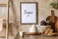 Stylish interior of kitchen space with wooden table, brown mock up photo frame, herbs, vegetables, tea pot, cups. Royalty Free Stock Photo