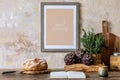 Stylish interior of kitchen space with wooden table, brown mock up photo frame, herbs, vegetables, tea pot, cups and kitchen. Royalty Free Stock Photo