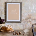 Stylish interior of kitchen space with wooden table, brown mock up photo frame, herbs, vegetables, tea pot, cups and kitchen. Royalty Free Stock Photo