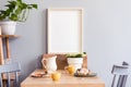 Stylish interior of kitchen space with wooden table with mock up photo frame, design chairs, decoration and furniture. Royalty Free Stock Photo