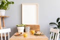 Stylish interior of kitchen space with wooden table with mock up photo frame, design chairs, decoration and furniture. Royalty Free Stock Photo