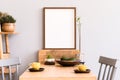 Stylish interior of kitchen space with wooden table with mock up photo frame, design chairs, decoration and furniture. Royalty Free Stock Photo