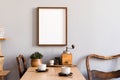 Stylish interior of kitchen space with wooden table with mock up photo frame, design chairs, decoration and furniture.