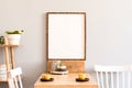 Stylish interior of kitchen space with wooden table with mock up photo frame, design chairs, decoration and furniture. Royalty Free Stock Photo