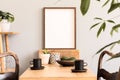 Stylish interior of kitchen space with wooden table with mock up photo frame, design chairs, decoration and furniture. Royalty Free Stock Photo