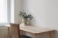 Stylish interior. Living room with vase, eucalyptus tree branches, old books on wooden table. Rattan chair near window