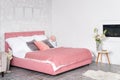 Stylish interior of modern bedroom. White and pink design of cozy bedroom with flowers. King-size bed with pink and grey Royalty Free Stock Photo