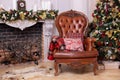 Stylish interior of room with Christmas fir tree and brown armchair. Beautiful cozy decorated living room for Christmas with firep Royalty Free Stock Photo