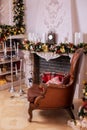 Stylish interior of room with Christmas fir tree and brown armchair. Beautiful cozy decorated living room for Christmas with firep Royalty Free Stock Photo