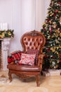 Stylish interior of room with Christmas fir tree and brown armchair. Beautiful cozy decorated living room for Christmas with firep Royalty Free Stock Photo