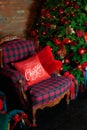 Stylish interior of room with Christmas fir tree and checkered armchair. Red sofa near big Christmas fir. Beautiful decorated livi Royalty Free Stock Photo
