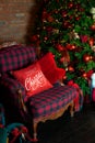 Stylish interior of room with Christmas fir tree and checkered armchair. Red sofa near big Christmas fir. Beautiful decorated livi Royalty Free Stock Photo