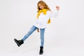 Stylish joyful caucasian girl in a white shirt and blue jeans in full growth posing on a white studio background with