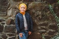 Stylish kid boy posing outdoors. Autumn fashion. People, fashion, lifestyle concept. Cute boy wears yellow hat, sweater, jacket