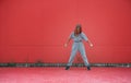 Stylish kid girl posing outdoors on red wall background. Young female dancer prepare performing. Copy space Royalty Free Stock Photo
