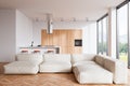 Stylish kitchen interior with countertop, couch and bar chairs near panoramic window