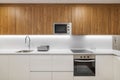 Stylish kitchen with modern furniture in white color with wooden cupboards for kitchenware. Contemporary style interior