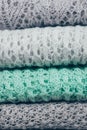 Stylish knitted pastel colored sweaters folded in stack. Winter and spring season knitwear clothing. Close up, copy space