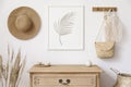 Stylish korean interior of living room with mock up poster frame, elegant accessories, dried flowers in vase, wooden shelf.