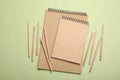 Stylish kraft notebooks and coloured pencils on light green background, flat lay Royalty Free Stock Photo