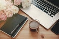 Stylish laptop, phone with empty screen, black notebook, coffee and peonies on rustic wooden table. Freelance concept. Girly Royalty Free Stock Photo