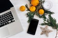 stylish laptop and phone with empty screen on white wooden background with christmas oranges and golden star and candle. flat lay Royalty Free Stock Photo