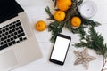 stylish laptop and phone with empty screen on white wooden background with christmas oranges and golden star and candle. flat lay Royalty Free Stock Photo