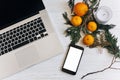 stylish laptop and phone with empty screen on white wooden background with christmas oranges and golden star and candle. flat lay Royalty Free Stock Photo