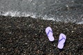 Stylish lilac flip lops on pebble beach near sea, above view. Space for text