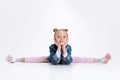 Portrait of little Caucasian cute girl in stylish outfit sitting in a twine on floor isolated over white studio Royalty Free Stock Photo