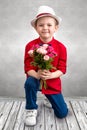 Stylish little boy down on one knee and gives a bouquet of roses.