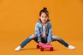 Stylish little child girl with skateboard in denim on orange background Royalty Free Stock Photo