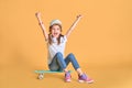 Stylish little girl child girl in casual with skateboard over yellow background Royalty Free Stock Photo