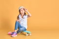 Stylish little girl child girl in casual with skateboard over yellow background Royalty Free Stock Photo