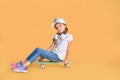 Stylish little girl child girl in casual with skateboard over yellow background Royalty Free Stock Photo