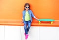 Stylish little girl child sitting with skateboard wearing a sunglasses and checkered shirt Royalty Free Stock Photo