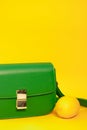 stylish little green purse or handbag on yellow background with a lemon nearby. Product composition photography. bag and Royalty Free Stock Photo